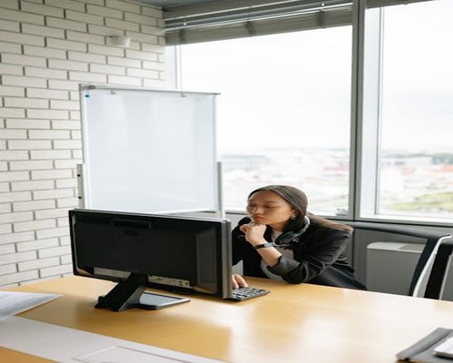 asian office worker doing light neck stretches in front of computer